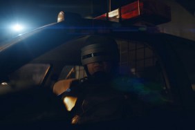 RoboCop sat in the driver's seat of a police car.