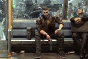Cyberpunk 2077: V holding a pistol while sitting on a metro car.