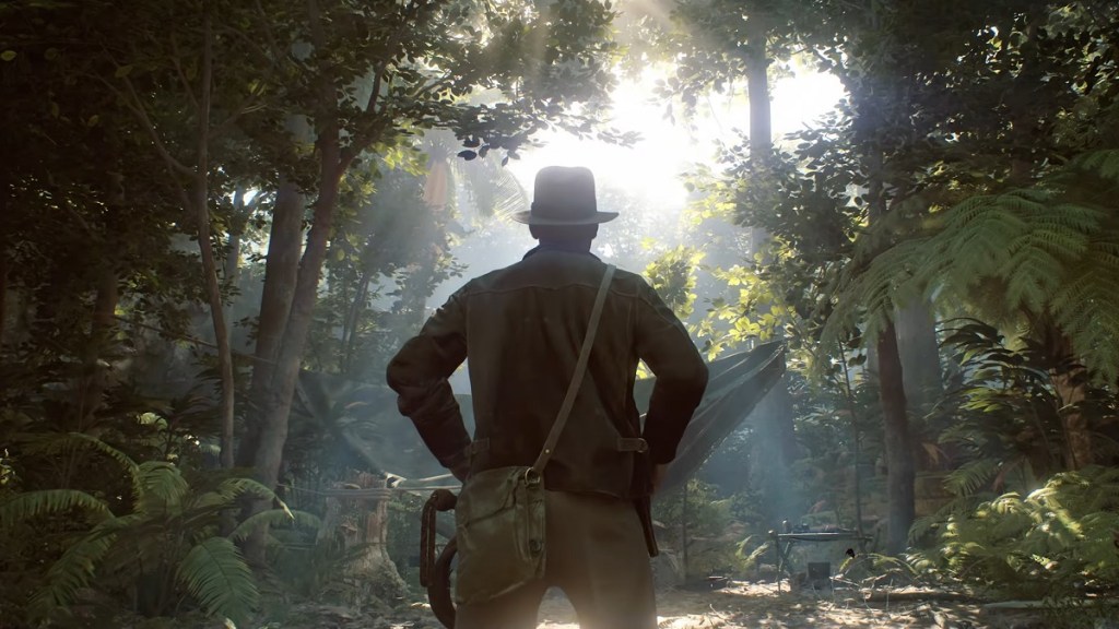The back of Indiana Jones as he looks out into a dense forest.